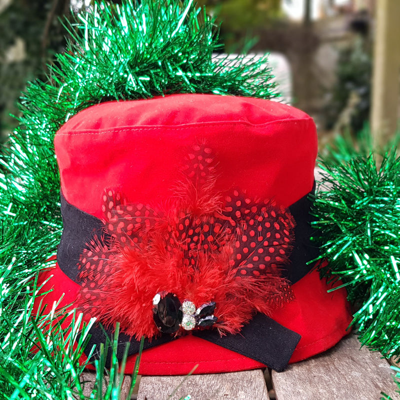 Red velour rain hat with black band with feathers and a jewl