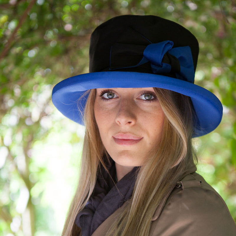 ladies black rain hat with royal blue bow and under brim on woman